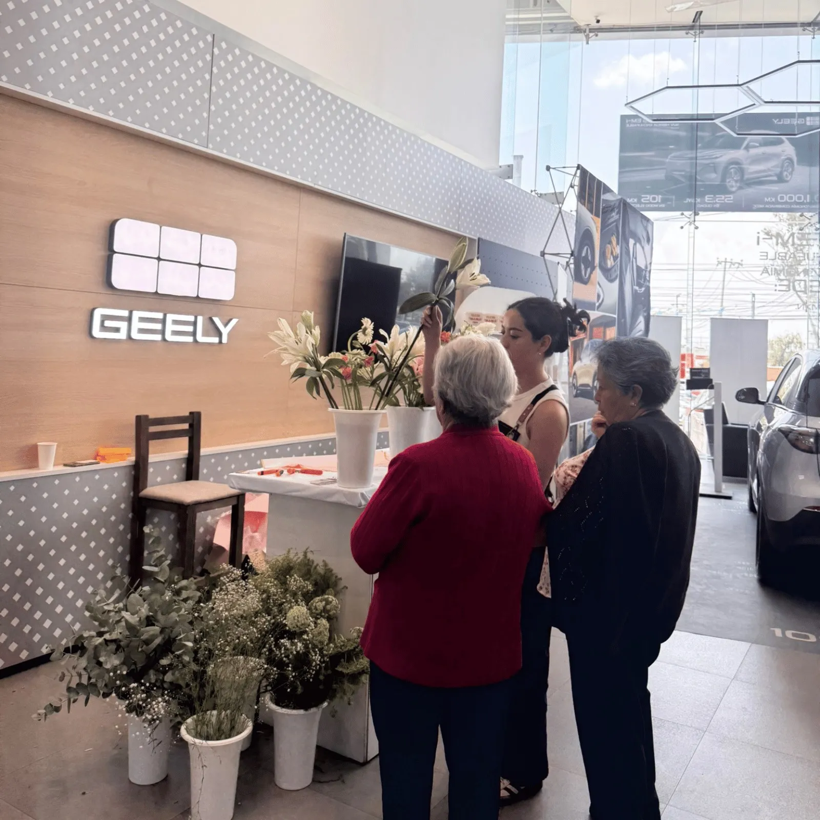 Zona de convivencia con mobiliario rústico y flores en el showroom de Geely Metepec