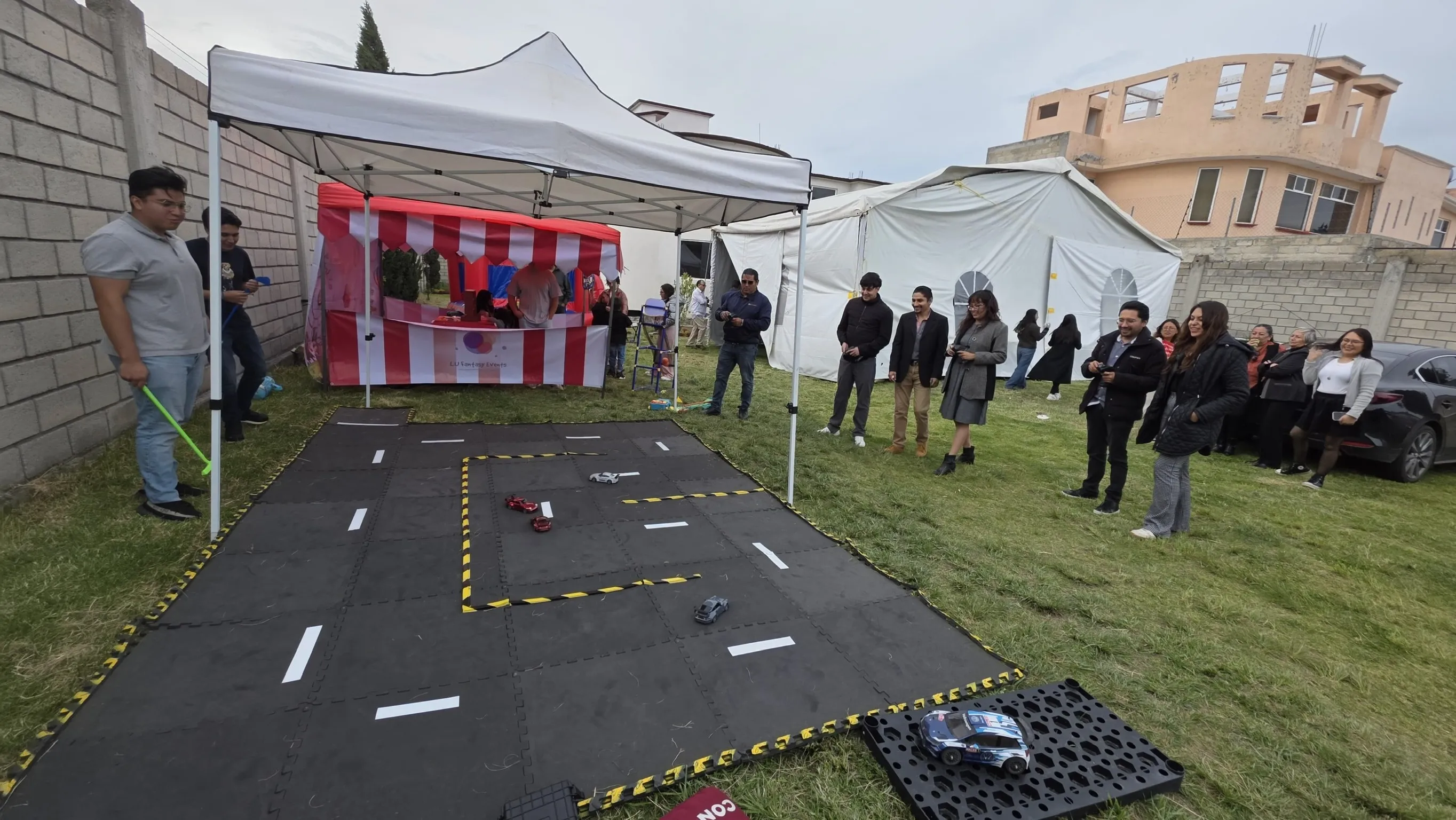 Participantes jugando con autos a control remoto junto a una Mini Feria de LU Fantasy